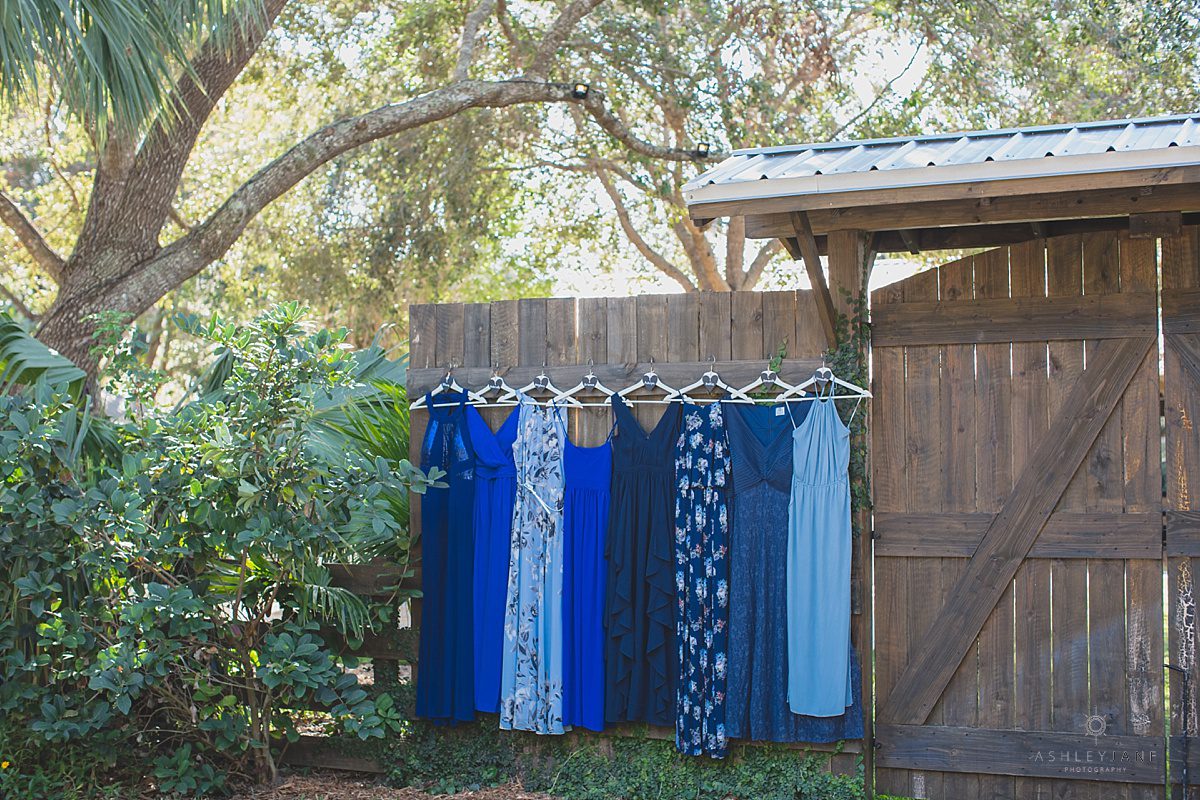 bridesmaid gowns hanging on fence rustic wedding outdoor blue hues 
