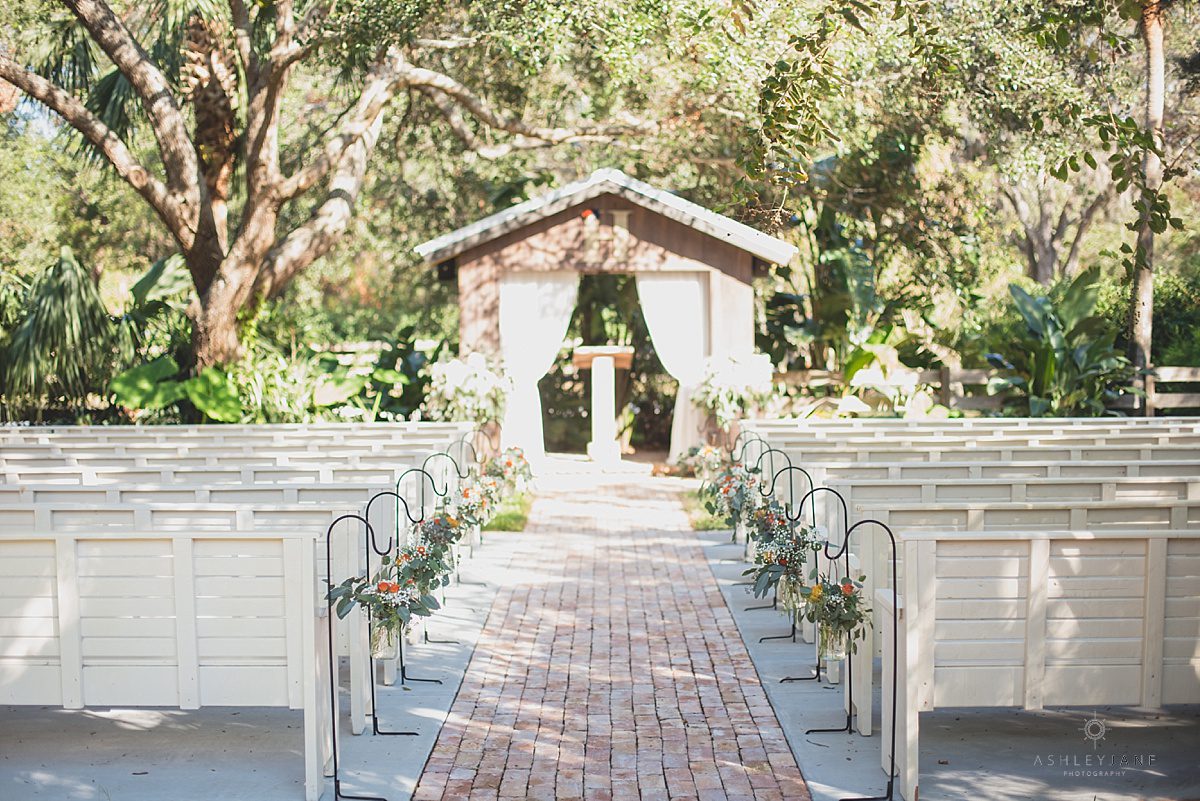 rustic outdoor wedding ceremony with eucalyptus and orange roses down the aisle