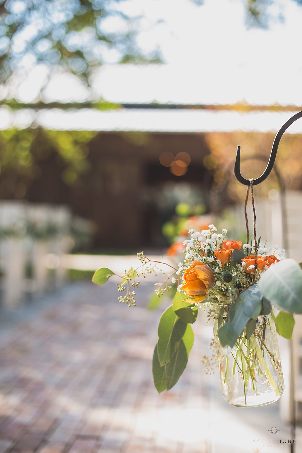 baby's breath, eucalyptus, and orange roses down the ceremony aisle