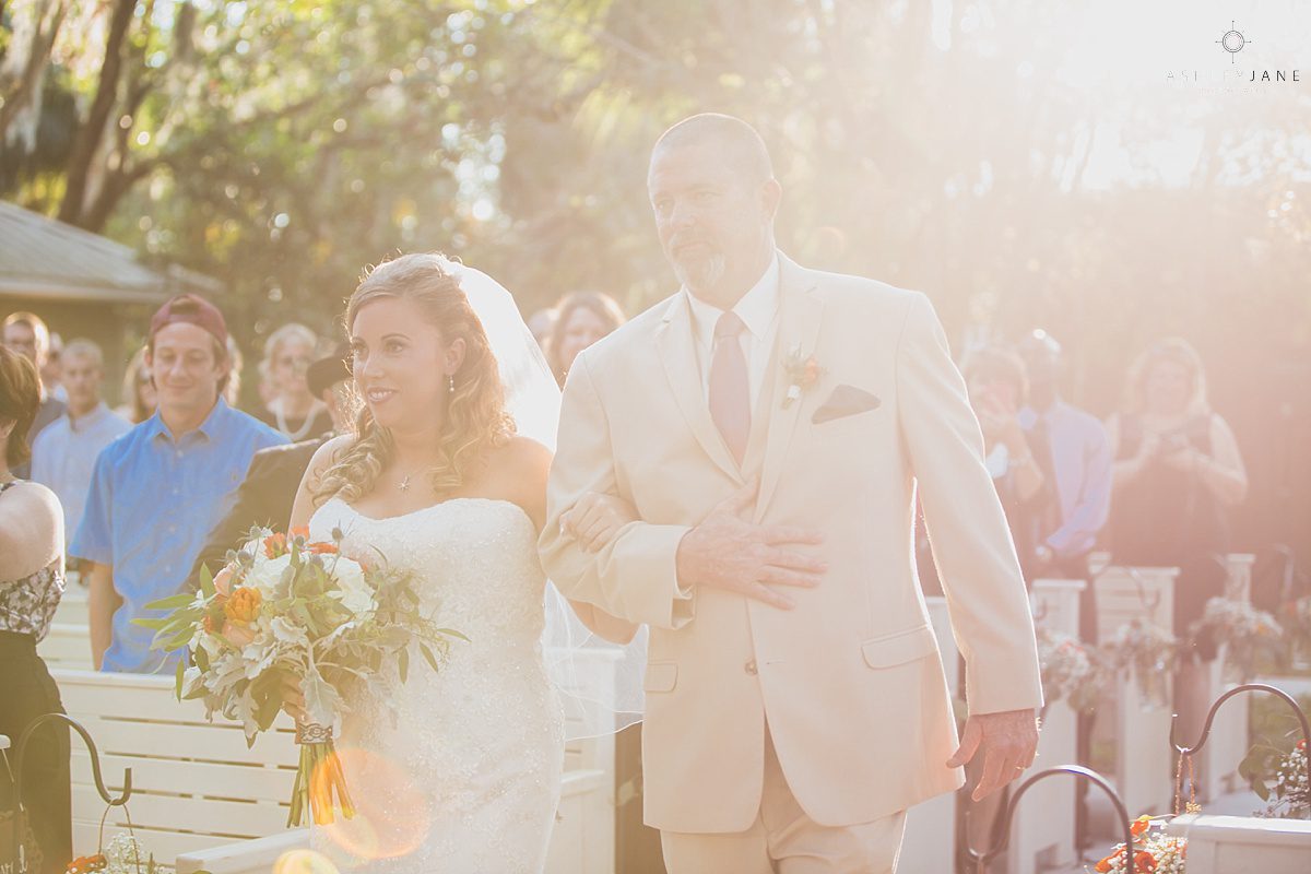 bride walking down the aisle with her father during sunset