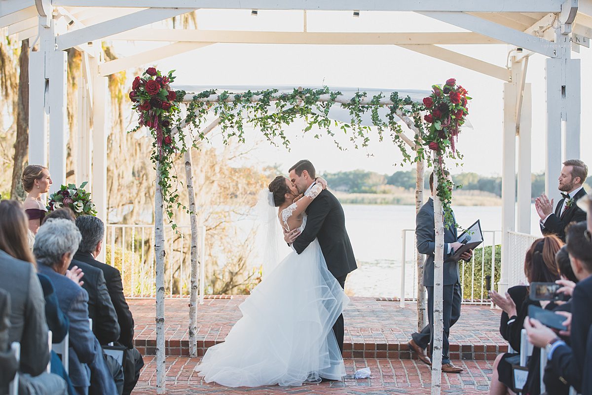 Elegant Rustic Cypress Grove Estate House Wedding| First kiss and husband and wife wedding outdoor lakeside wine color winter wedding shot by orlando wedding photographer