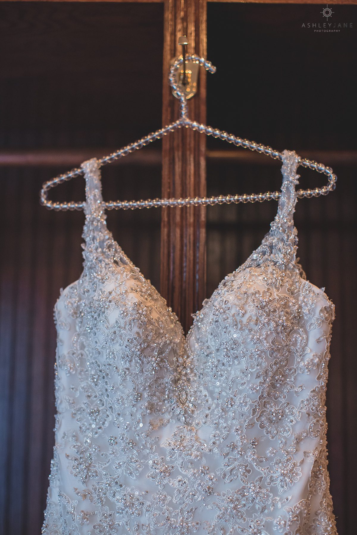 Brides wedding dress hanging in bridal suite with beaded hanger at Luxmore Grande Estate near Orlando